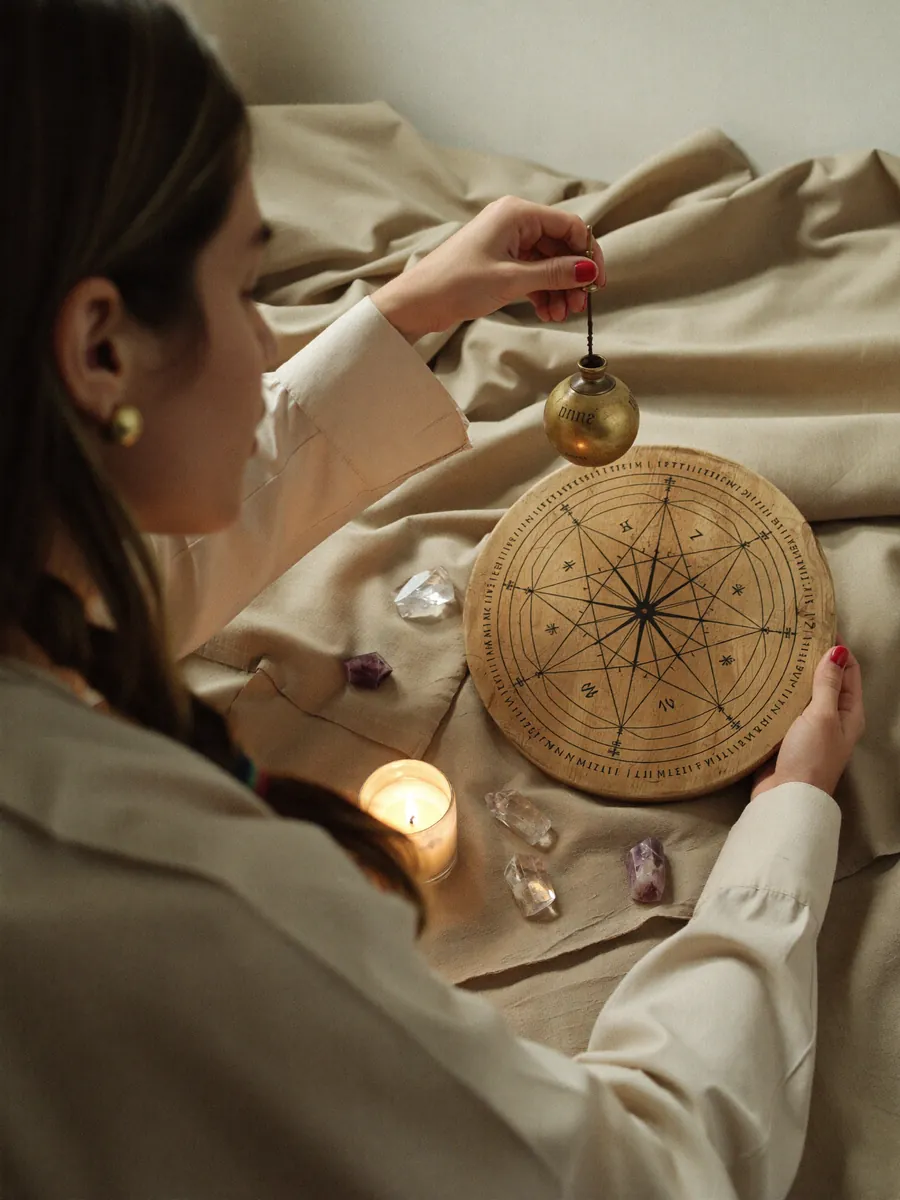 Vitoria com um pêndulo sobre a mesa quântica, entre cristais e uma vela